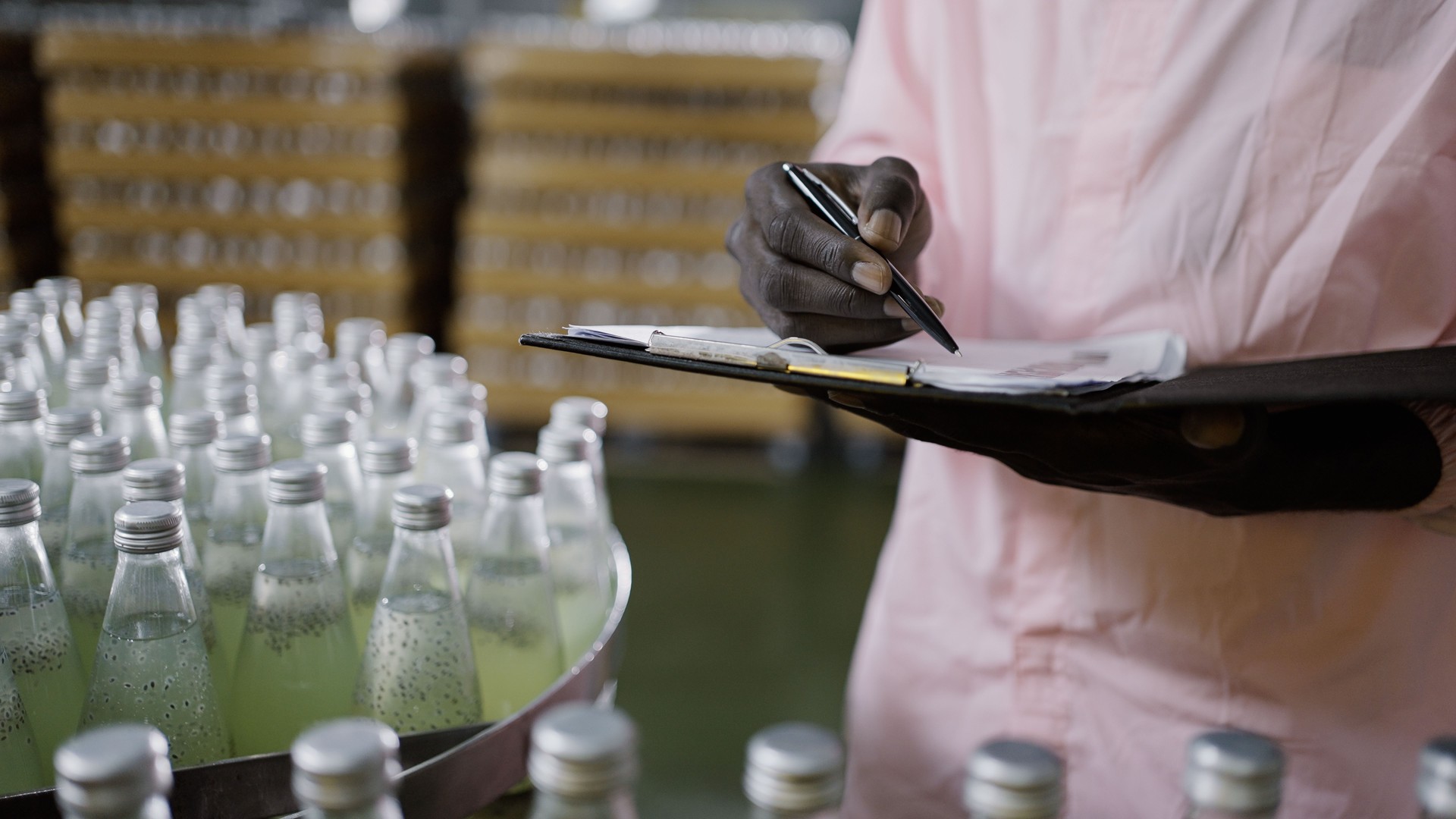 Worker counting number of juice bottles in factory