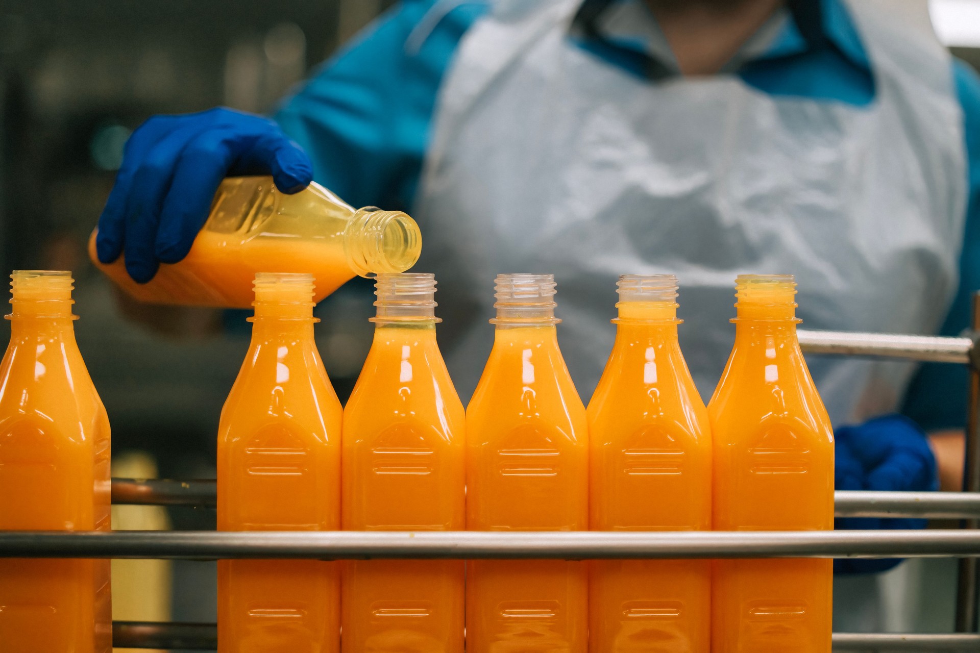 Asian factory worker topping up orange juice in production line
